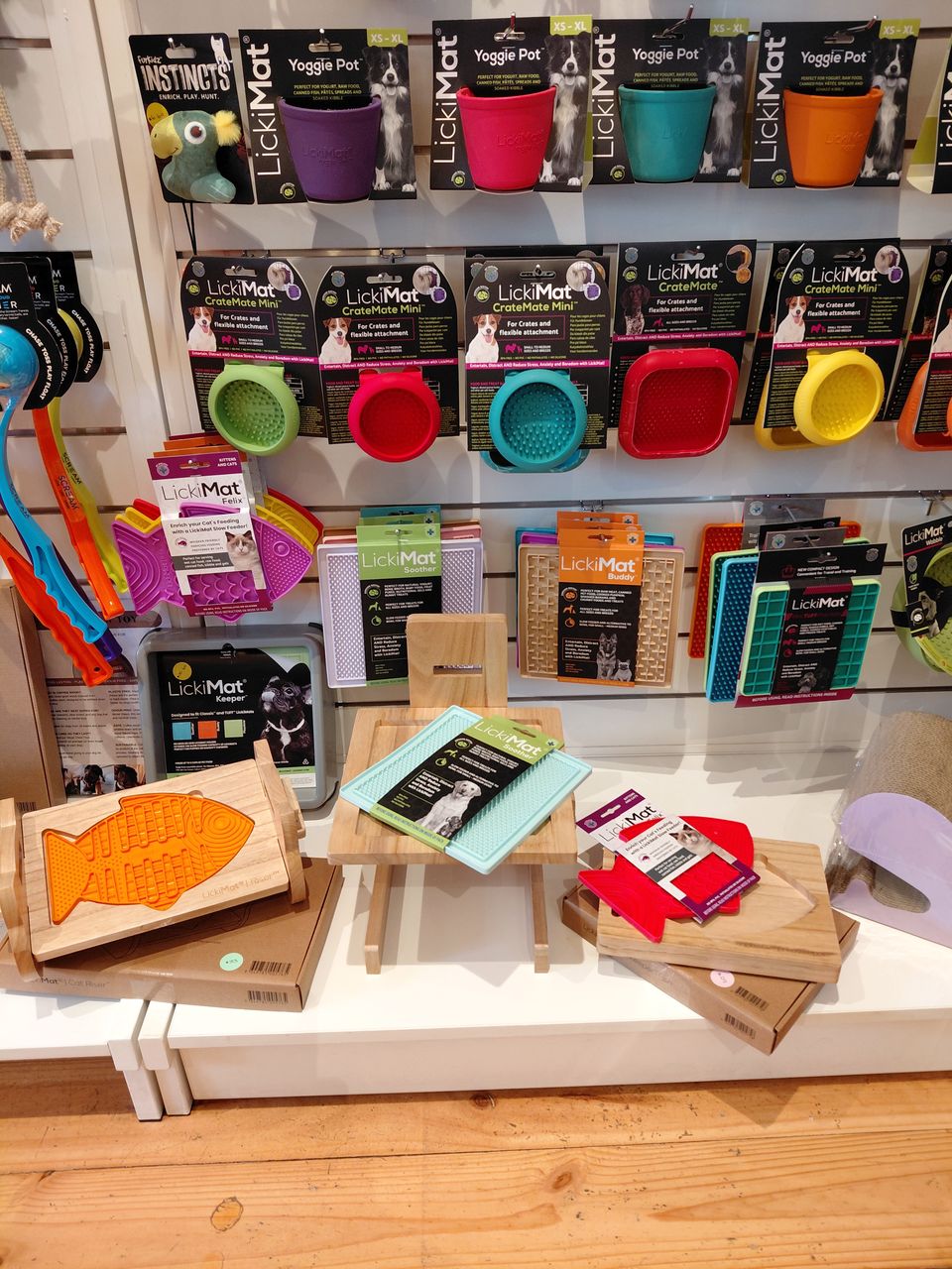 A wall of colourful LickiMat enrichment mats and wooden holders in the shop